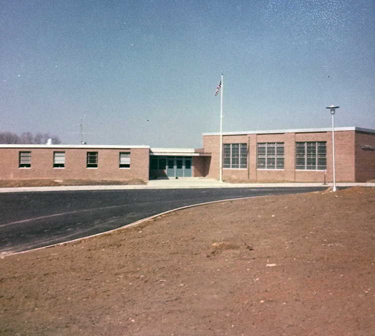 Photograph of Stenwood Elementary School main entrance in early 1964, shortly after the school opened. It is late winter or early spring and the school grounds are exposed dirt. 